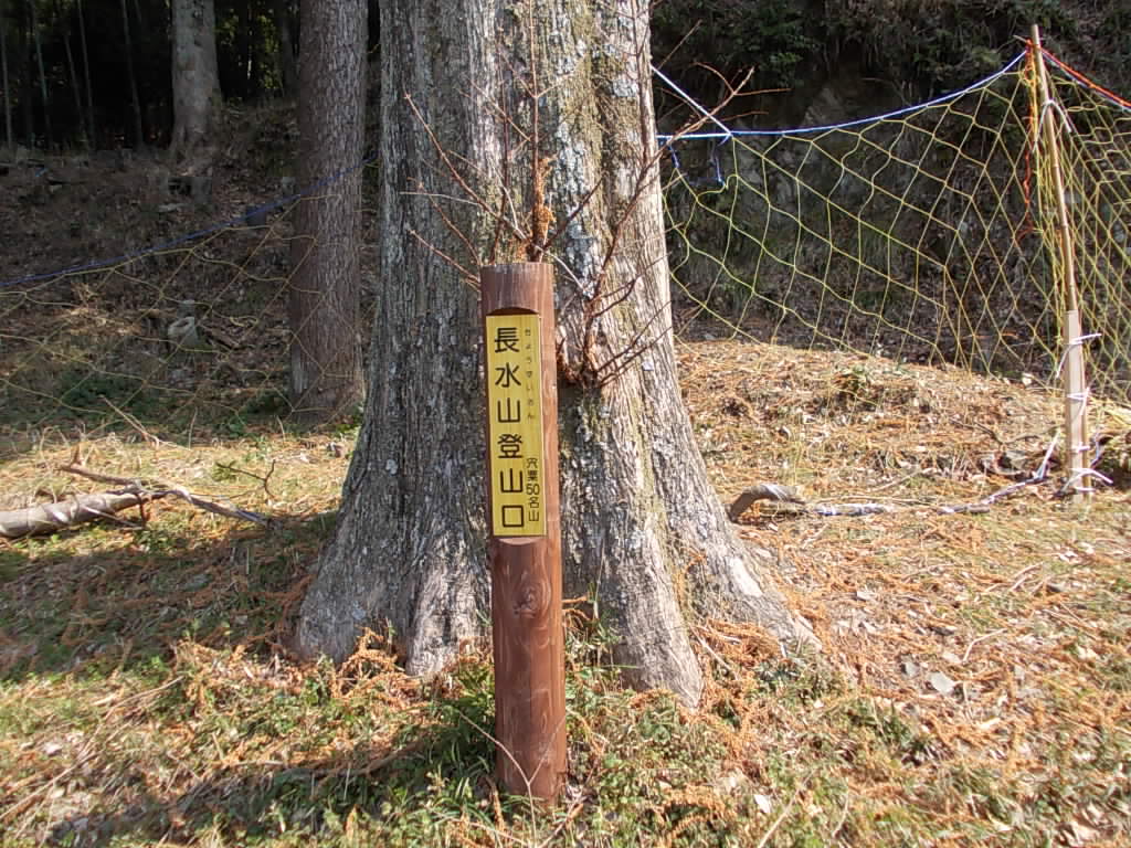 10:30 小学校の駐車場にある登山口の案内柱。後ろのネットを抜けていきます。