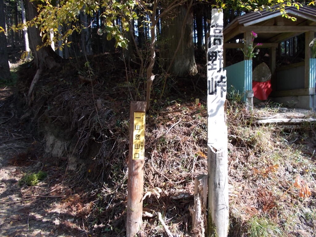 11：04　お地蔵さんのすぐ横にある標柱。この横の林道を入ってすぐに右です。この林道を歩くとおそらく山頂手前の広場につながっていると思います。（未確認）